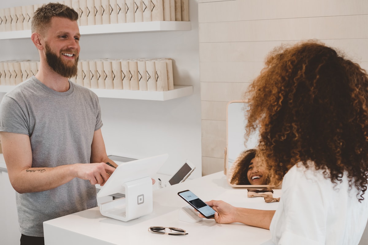 A shop assistant serving a customer at a bright retail counter
